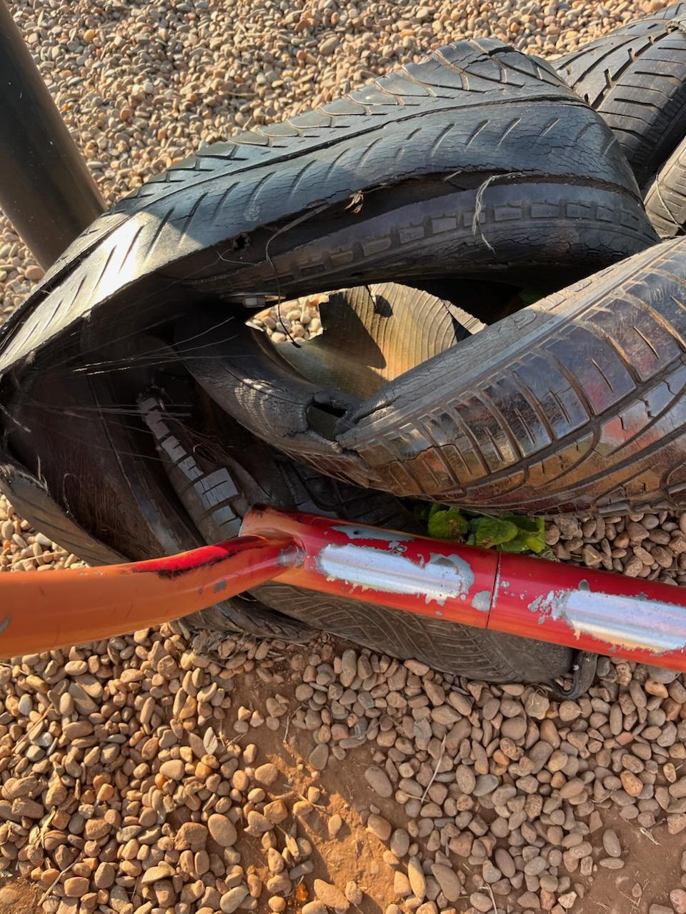 A pile of tires on a gravel surface
AI-generated content may be incorrect.